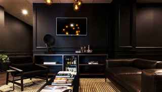 Sophisticated room with dark walls and furniture, TV, and bar fridge