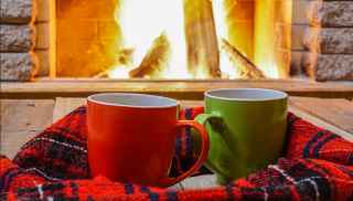 Two mugs on a blanket in front of a fireplace