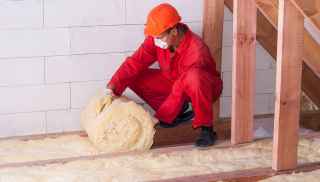 Person wearing protective clothing laying insulation