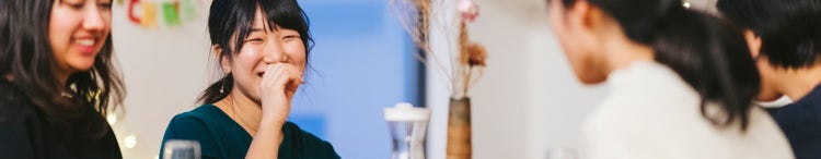 Four women smiling at a dinner table.
