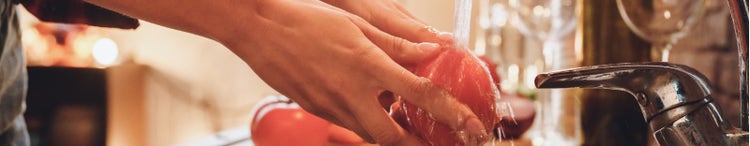 Vegetables being washed at the kitchen sink.