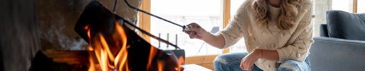 Woman adjusting burning logs with a poker.