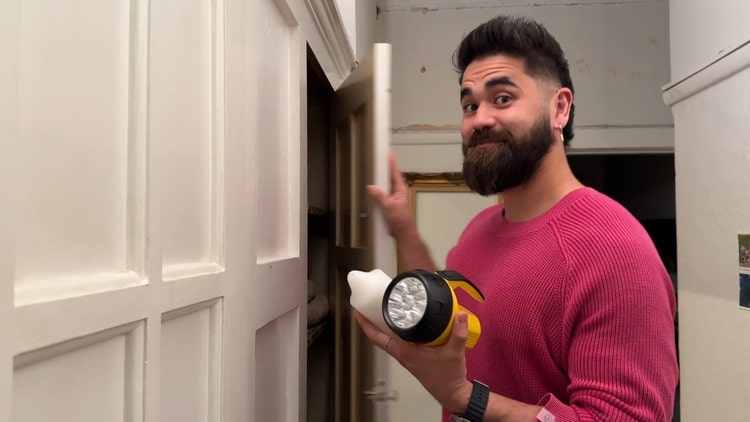 Man retrieving candle and torch from a cupboard.