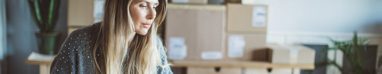 woman in front of pile of boxes looking at computer