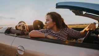 Woman in convertible car with happy dog