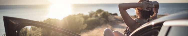 woman lying on car bonnet watching sunset