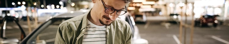 Man standing in front of car at night.