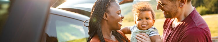 couple with baby standing beside car