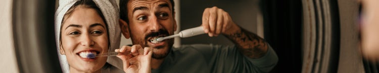 couple brushing teeth in front of mirror