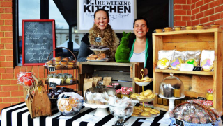 Two happy people behind a market stall