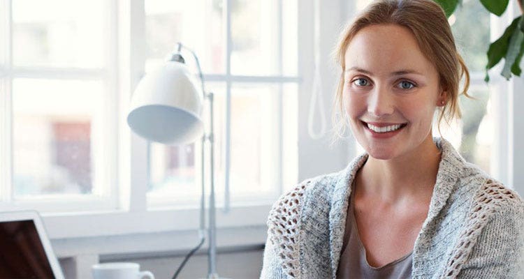 Woman sole trader sitting at her office desk smiling