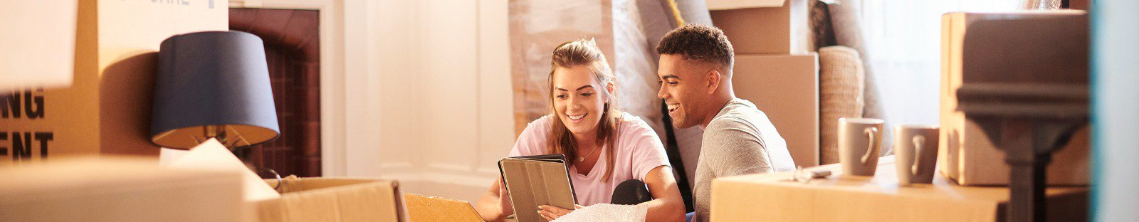 Couple sitting on the floor surrounded by packing boxes at home