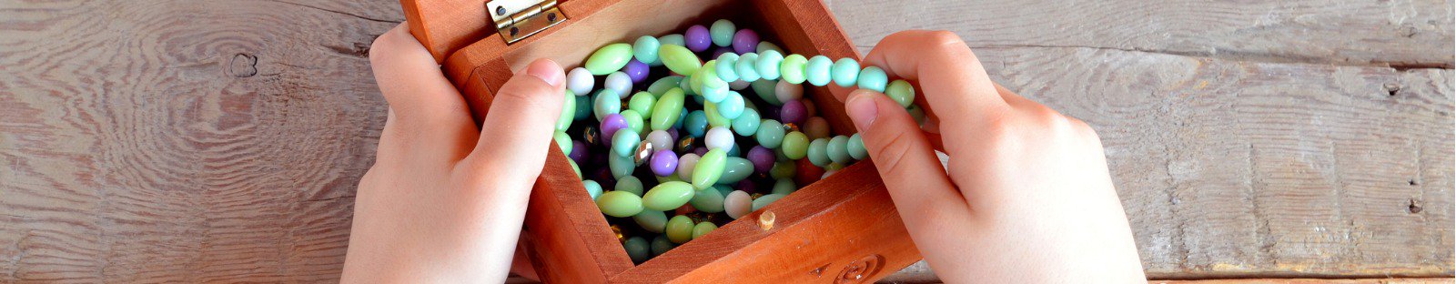 Girls hands opening wooden box full of jewellery