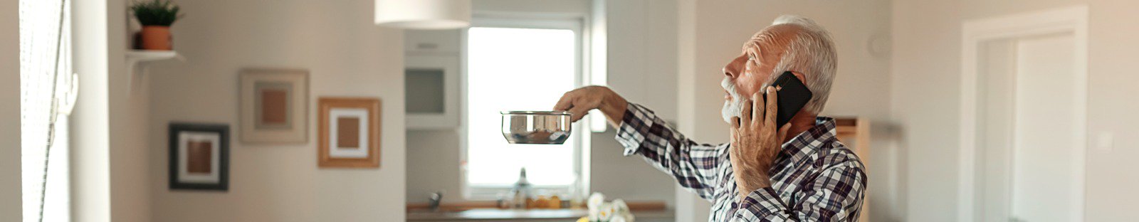 man holding pot catching water from leaking from
