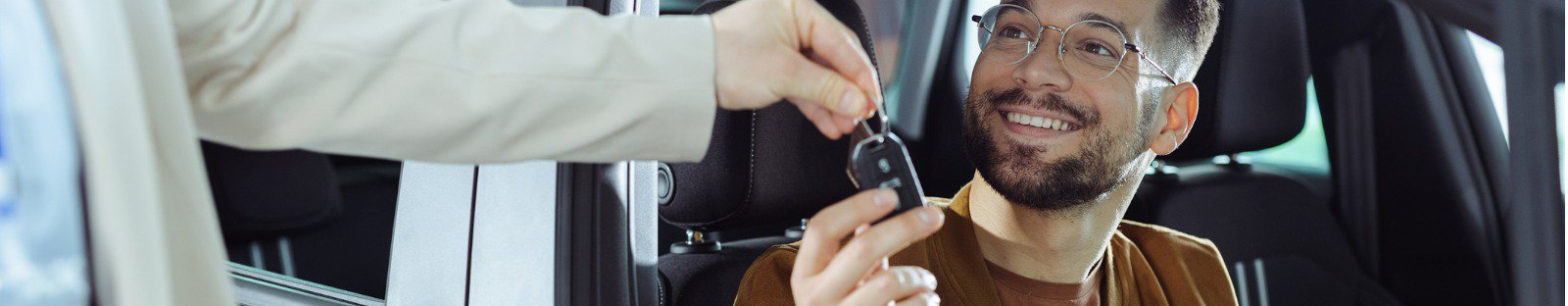 Man in car receiving new car keys