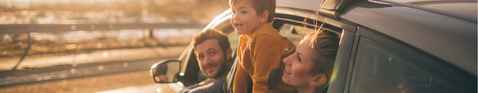 man, woman and young boy looking out of parked car at landscape