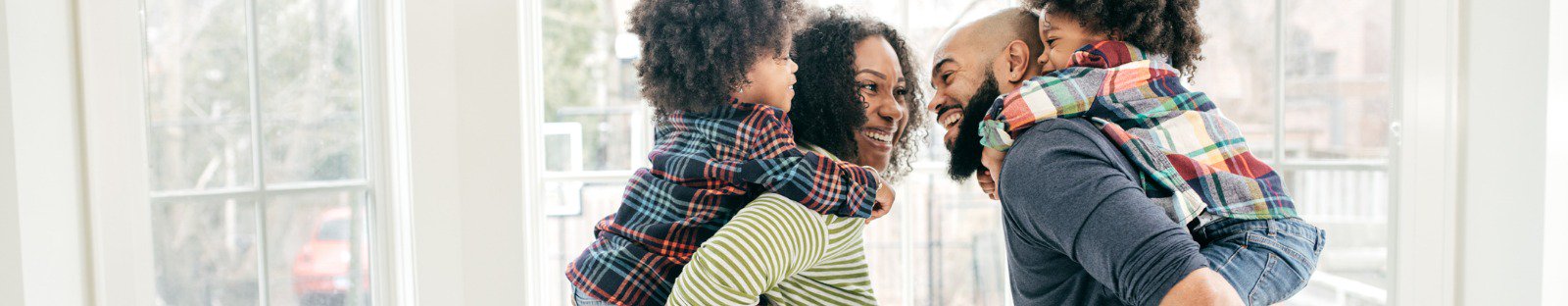 Smiling man and woman each with a child on their back