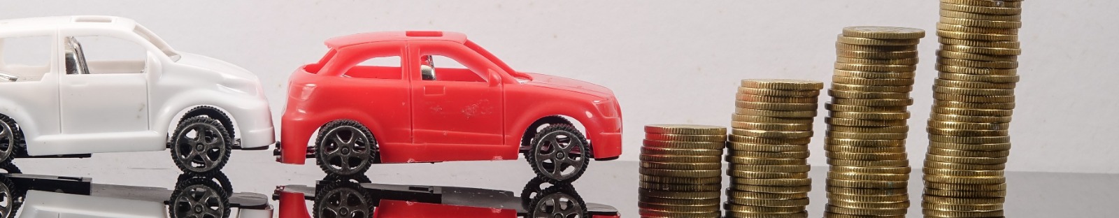 Toy cars lined up next to gold coins