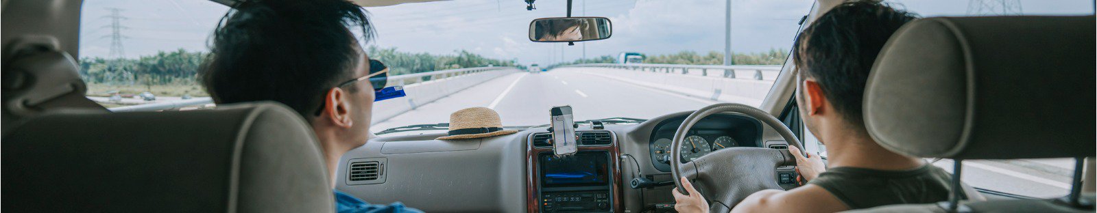 Two men driving a car on the highway