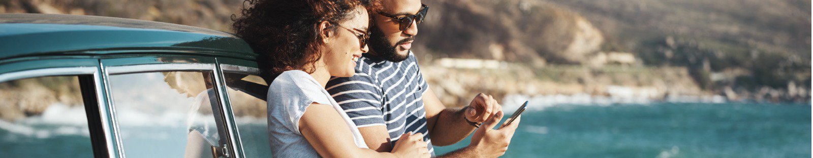 Two people next to car looking at mobile phone