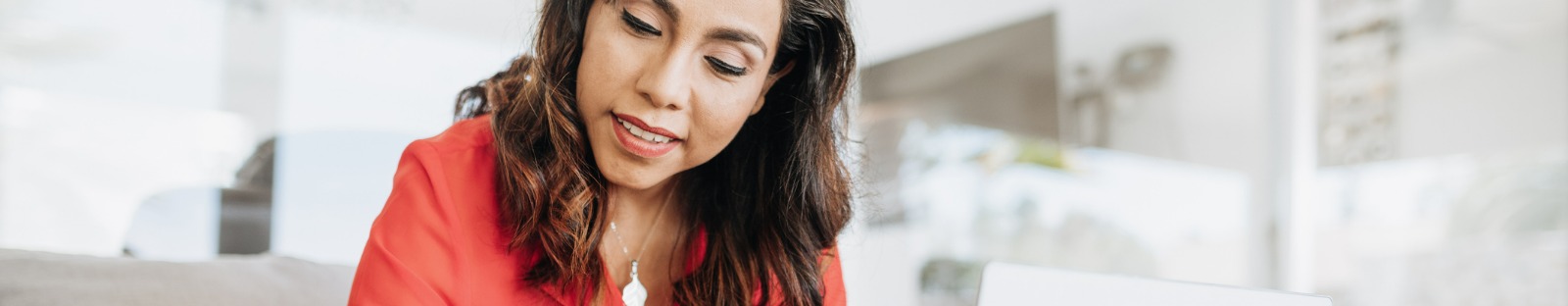 woman at home working on laptop and looking at paper