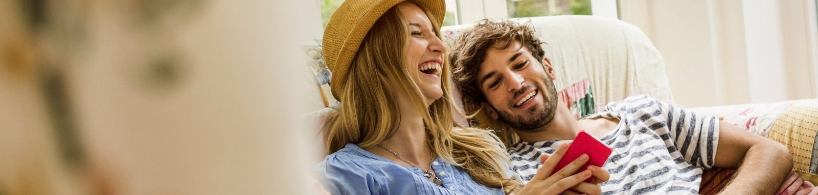 Young couple on the couch using a phone