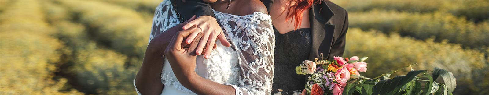 A couple standing in a field on their wedding day with weddings rings on