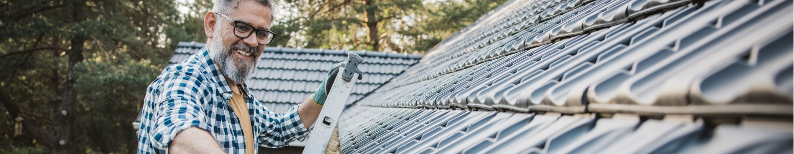 Man cleaning leaves from roof gutter