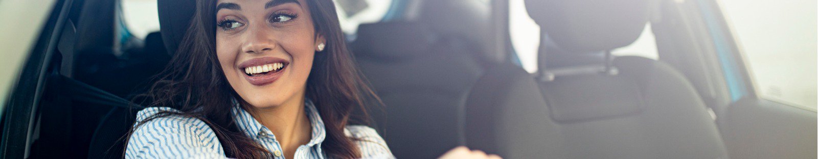 Smiling woman behind steering wheel of a car