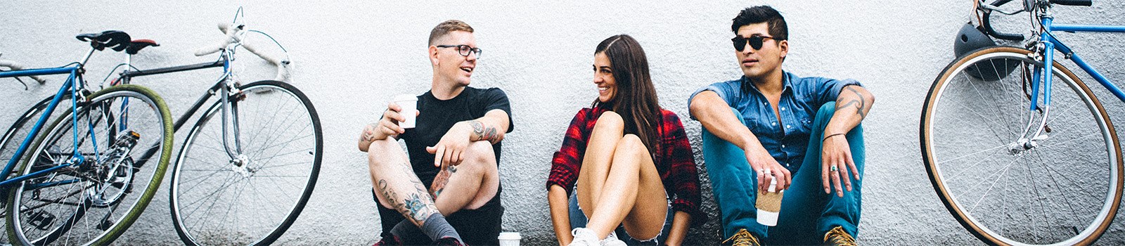 Three young adults sitting against a wall