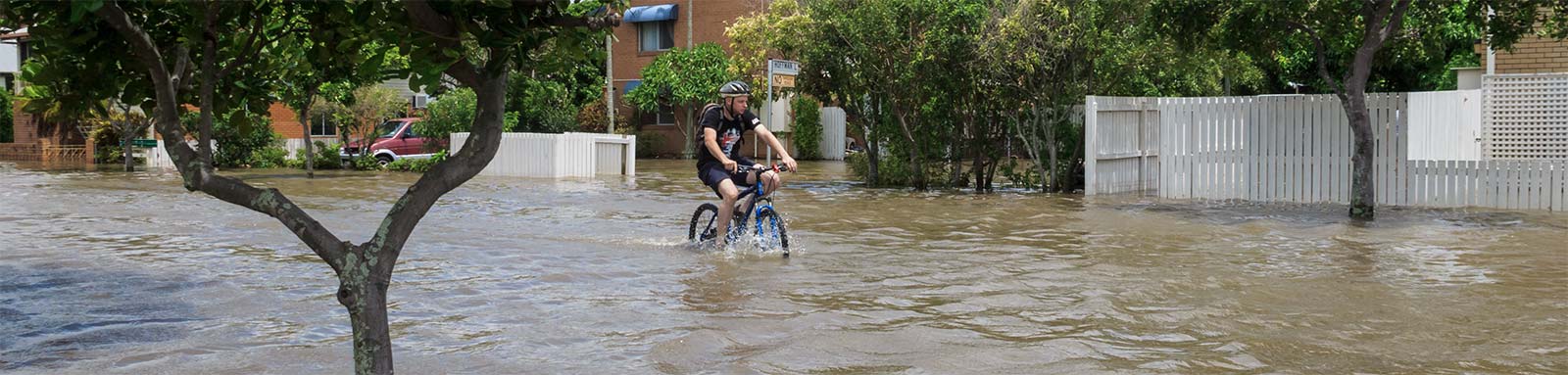 Boy cycling through flood waters