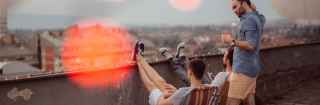 Three young men overlooking a city on a rooftop