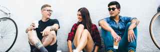 Three young adults sitting against a wall