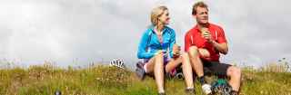 Couple wearing exercise gear sitting on a grass hill