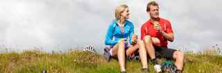 Couple wearing exercise gear sitting on a grass hill