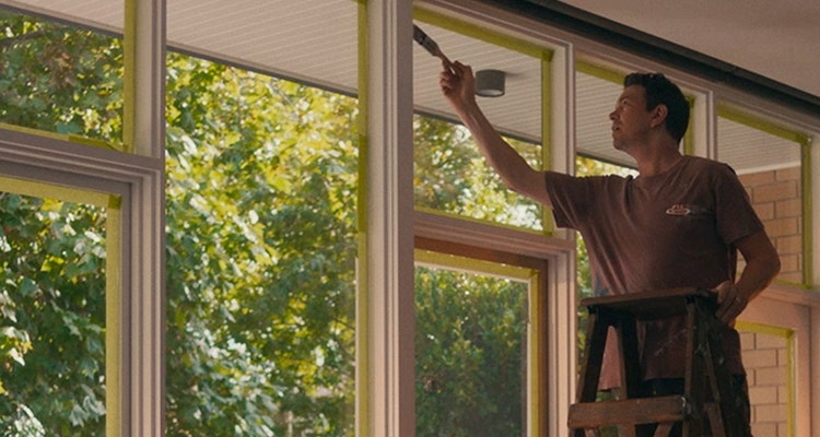 Man on ladder painting window