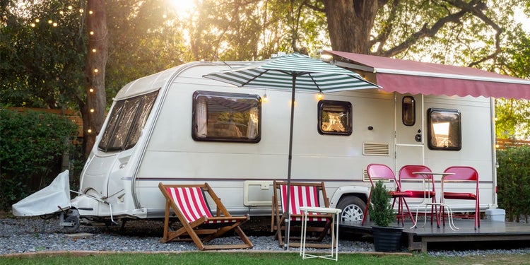 Sunbeds and folding chairs in front of caravan