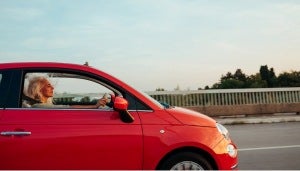 Woman drives small red car with the windows rolled down